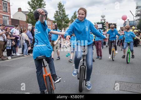 Kinder, die einräder in der Parade auf der High Street im Stockton Internationale Riverside Festival, England, Großbritannien Stockfoto