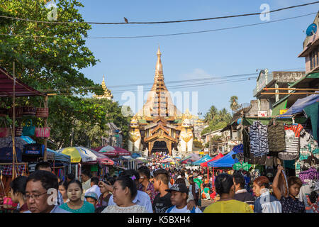 Die Shwedagon Pagode östlichen Eingang und eine Menge Leute auf einem Markt auf der Gyar Tawya Straße in Yangon, Myanmar. Stockfoto