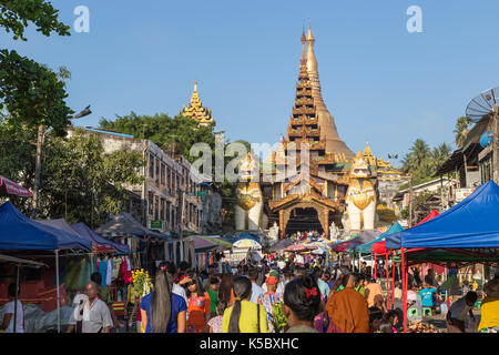 Die Shwedagon Pagode östlichen Eingang und eine Menge Leute auf einem Markt auf der Gyar Tawya Straße in Yangon, Myanmar. Stockfoto