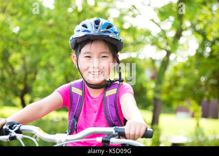 Glückliches Mädchen reiten Fahrrad im Park Stockfoto