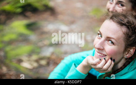 Zwei junge Frauen, die an der Kamera und lächelnd im Freien Stockfoto