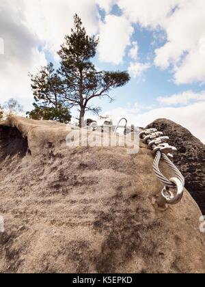 Bügeleisen verdrilltes Seil zwischen die Felsen in Kletterer gestreckt patch Klettersteig. Seil fest im Block durch Schrauben Karabinerhaken. Detail der Tampen in s verankert Stockfoto