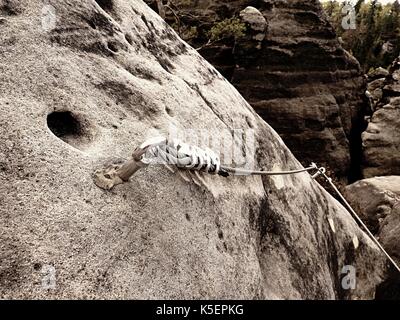 Bügeleisen verdrilltes Seil zwischen die Felsen in Kletterer gestreckt patch Klettersteig. Seil fest im Block durch Schrauben Karabinerhaken. Detail der Tampen in s verankert Stockfoto