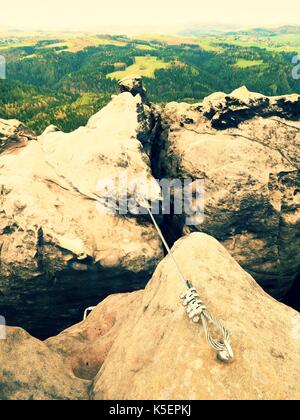 Bügeleisen verdrilltes Seil zwischen die Felsen in Kletterer gestreckt patch Klettersteig. Seil fest im Block durch Schrauben Karabinerhaken. Detail der Tampen in s verankert Stockfoto