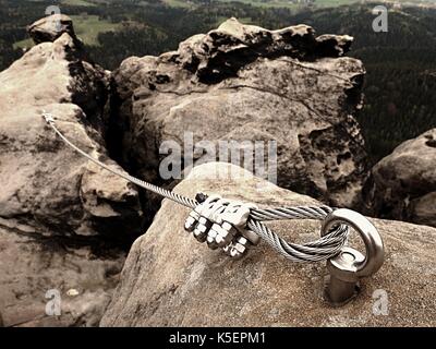 Bügeleisen verdrilltes Seil zwischen die Felsen in Kletterer gestreckt patch Klettersteig. Seil fest im Block durch Schrauben Karabinerhaken. Detail der Tampen in s verankert Stockfoto