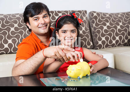 Indische Vater und Tochter Geld sparen Sparschwein Zukunft Bildung Stockfoto