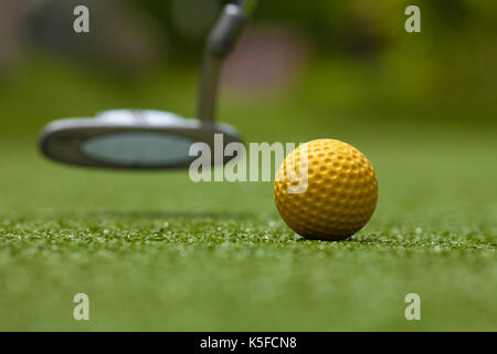 Golf Club und gelbe Kugel auf Kunstrasen Stockfoto