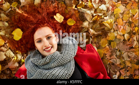 Ingwer liegende Frau auf Blättern im Park im Herbst, Ansicht von oben Stockfoto