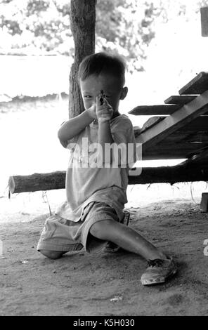 Karen burmesischen Flüchtlingskind Punkte eine Spielzeugpistole bei einem Camp im Nordwesten von Thailand. September, 1996. Stockfoto