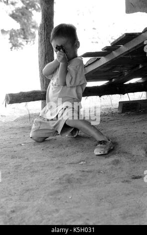 Karen burmesischen Flüchtlingskind Punkte eine Spielzeugpistole bei einem Camp im Nordwesten von Thailand. September, 1996. Stockfoto