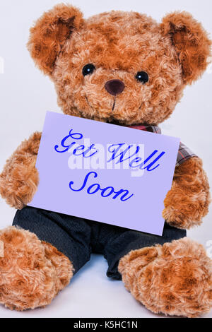 Cute teddy bear Holding ein violettes Schild mit der Aufschrift auch bald auf weißem Hintergrund Stockfoto