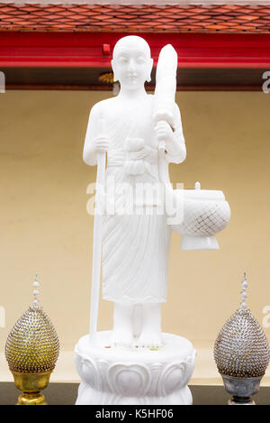 Weißer Buddha Statue in Wanderung Mission. Stehender Buddha Statue mit Mönch Schüssel oder Almosen Schüssel und Regenschirm. Thailand. Stockfoto