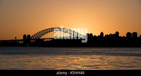 Die Sydney Harbour Bridge und der Sydney Skyline der Stadt in einem leuchtenden orange Sonnenuntergang silhouette Foto. New South Wales, Australien. Stockfoto