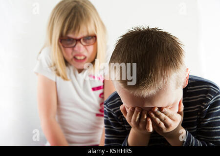 Junge traurig, wie er von einem wütenden Mädchen abgeholt wird. Stockfoto