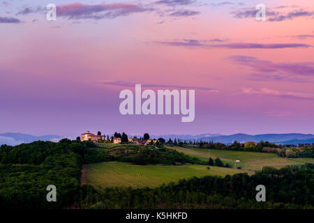 Typische tuscanian Landschaft mit einem Bauernhaus auf einem Hügel, Weinberge und Bäume bei Sonnenaufgang Stockfoto