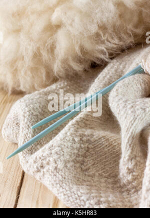 Gestrick aus natürlichen Wolle, Stricknadeln und Wolle auf alten hölzernen Hintergrund Stockfoto