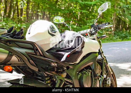 Bild von einem Motorrad auf der Landstraße in einem Wald geparkt Stockfoto