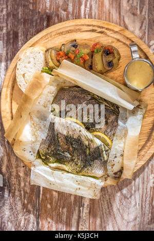 Gebackener Wolfsbarsch serviert mit gegrilltem Gemüse und Pilzen Stockfoto