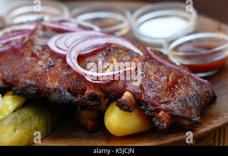 Rack mit Grill geröstet Schweinerippchen mit Zwiebeln, Pfeffer und Saucen, Nahaufnahme, hohe Betrachtungswinkel Stockfoto
