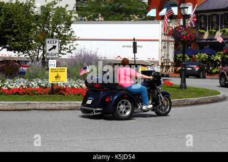 Bikerin auf einem Motortrike, die während der Bike Week in Gettysburg, Adams County, Pennsylvania, USA, am Schild „Town Throttle Down“ am Lincoln Square vorbeifährt Stockfoto