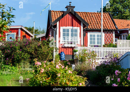 Karlskrona, Schweden - 28. August 2017: Reisedokumentation der Stadt Umgebung. Rote und weiße Zuteilung Kabine und Garten mit Blumen. Blaue Milch Fass Stockfoto