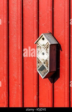 Kleines Insekt Hotel oder Bug Hotel auf rotem Holz- wand. Stockfoto
