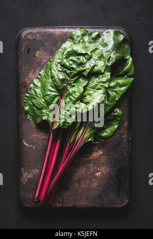 Frischen Mangold die Blätter auf dunklen Rusty Hintergrund. Tabelle Draufsicht frische organische Green Food Stockfoto