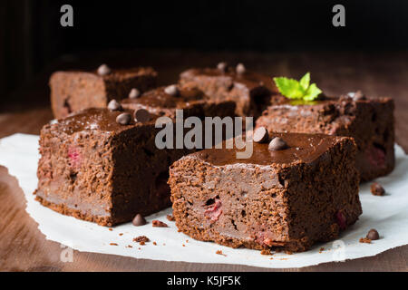 Dark chocolate Brownies mit mint Blatt auf hölzernen Tisch dekoriert. Detailansicht horizontale Zusammensetzung Stockfoto