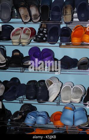 Clogs / Klinische Schuhe auf einem Schuhgestell in einer medizinischen Umkleidekabinen. VEREINIGTES KÖNIGREICH. Stockfoto