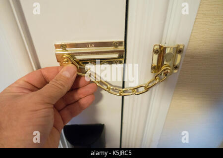 Personen, Hand, halten Sie ein Hotel oder eine Tür, auf der Innenseite der Kette Hotel Zimmer entweder zu entsperren oder sperren Tür für Sicherheit, England, Großbritannien Stockfoto