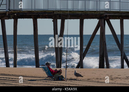 Belmar, NJ USA - September 9, 2017 - Fischer und Möwe am Strand mit Meeresrauschen im Hintergrund. Redaktionelle Verwendung. Stockfoto