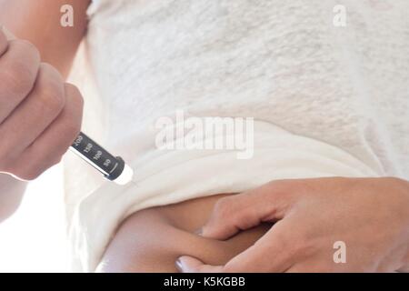 Frau injizieren sich im Bauch. Stockfoto