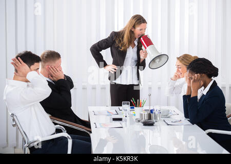 Unglücklich Geschäftsfrau Schreien durch Megafon auf Geschäftsleute in Office Stockfoto