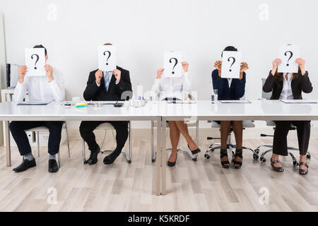 Geschäftsleute Holding Fragezeichen Zeichen vor ihrem Gesicht Stockfoto