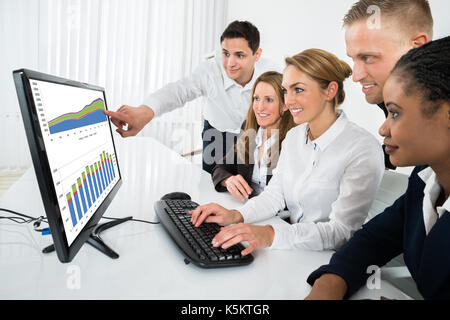 Gruppe der Multirassischen Geschäftsleute auf der Suche nach Grafik auf dem Computer im Büro Stockfoto