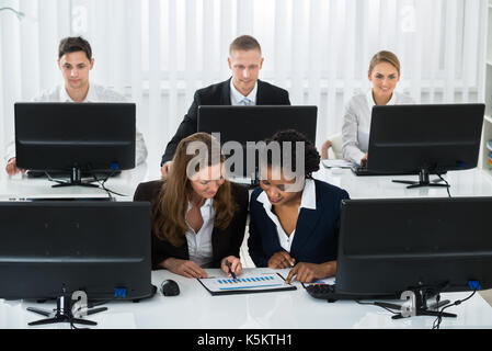 Zwei Unternehmerinnen gemeinsam diskutieren auf Graph am Arbeitsplatz Stockfoto