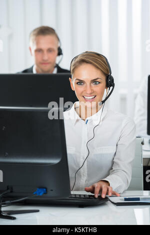 Junge weibliche Mitarbeiter mit Headset das Arbeiten am Computer in Call Center Stockfoto