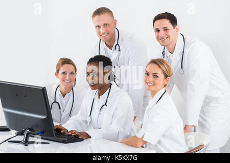 Gruppe von männlichen und weiblichen Ärzten am Computer am Schreibtisch im Krankenhaus Suchen Stockfoto