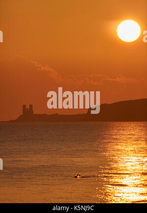 Herne Bay, Kent, Großbritannien. 10. September 2017: UK Wetter. Sonnenaufgang über Reculver Towers, von Herne Bay gesehen wie der Regen Wolken weg bewegen. Ein Schwimmer nimmt am frühen Morgen dip auf einem kühlen Sonntag Morgen. Mehr Sonnenschein und Duschen sind für die kommende Woche prognostiziert. Credit: Alan Payton/Alamy leben Nachrichten Stockfoto