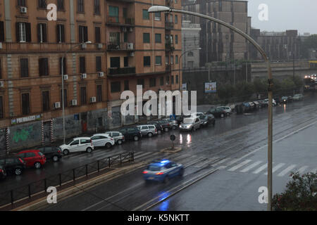 Geparkte Autos und ein Polizeiauto im Regen an der Via Prenestina. Rom, Italien. Stockfoto