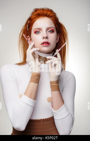 Schöne Frau vor Plastische Chirurgie Operation Kosmetologie. Beauty Portrait Fashion Concept. Junge Rote Haare Mädchen holding Spritzen in die Hände mit Korr