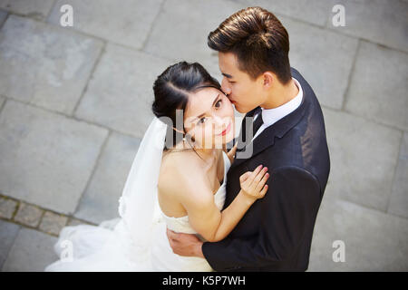 Junge asiatische Braut und Bräutigam umarmen Küssen tanzen in Open Air, hohe Blickwinkel betrachten. Stockfoto