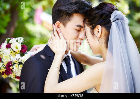 Junge asiatische Braut und Bräutigam küssen bei der Hochzeit Zeremonie Stockfoto