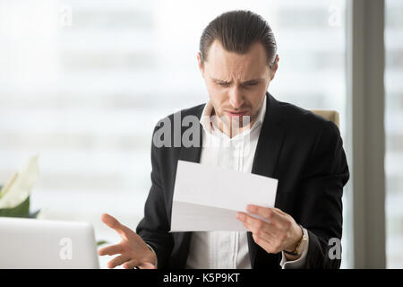 Frustrierte junge Unternehmer bei unübersichtlichen Schreiben in Büros suchen Stockfoto