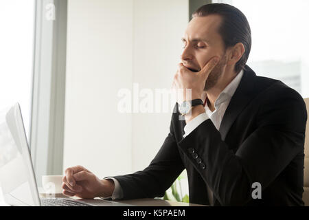 Müde, schläfrig Geschäftsmann Gähnen vor Laptop am Arbeitsplatz Stockfoto