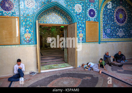 Provinz Fars, Shiraz, Iran - 18. April 2017: Gespiegelte Mausoleum und Moschee von Sayyed Alaeddin Hossein, muslimischen Gemeindemitglieder sitzen vor dem ENTRA Stockfoto