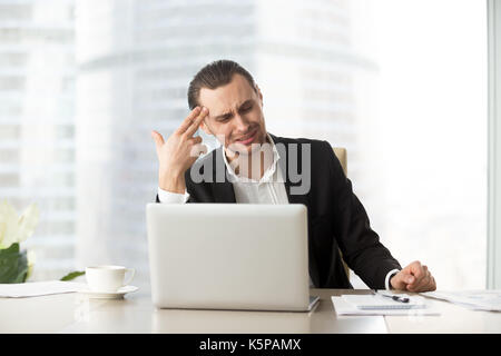 Distressed Geschäftsmann soll Finger Pistole an den Kopf bei der Arbeit. Stockfoto