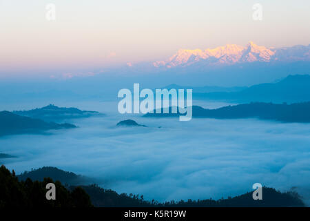 Tops von weit entfernten Himalaya Berggipfeln leuchten rot von Morgen Sonnenaufgang Licht über ein wogendes Meer von Wolken aus dem Bandipur, Nepal gesehen Stockfoto