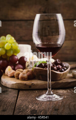 Rotwein mit Käse-Vielfalt. Essen-Hintergrund.  Frische Snacks auf Holz Stockfoto