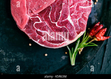 Fleisch. Rohes Fleisch. Rindersteak auf schwarz mit Kräutern Stockfoto